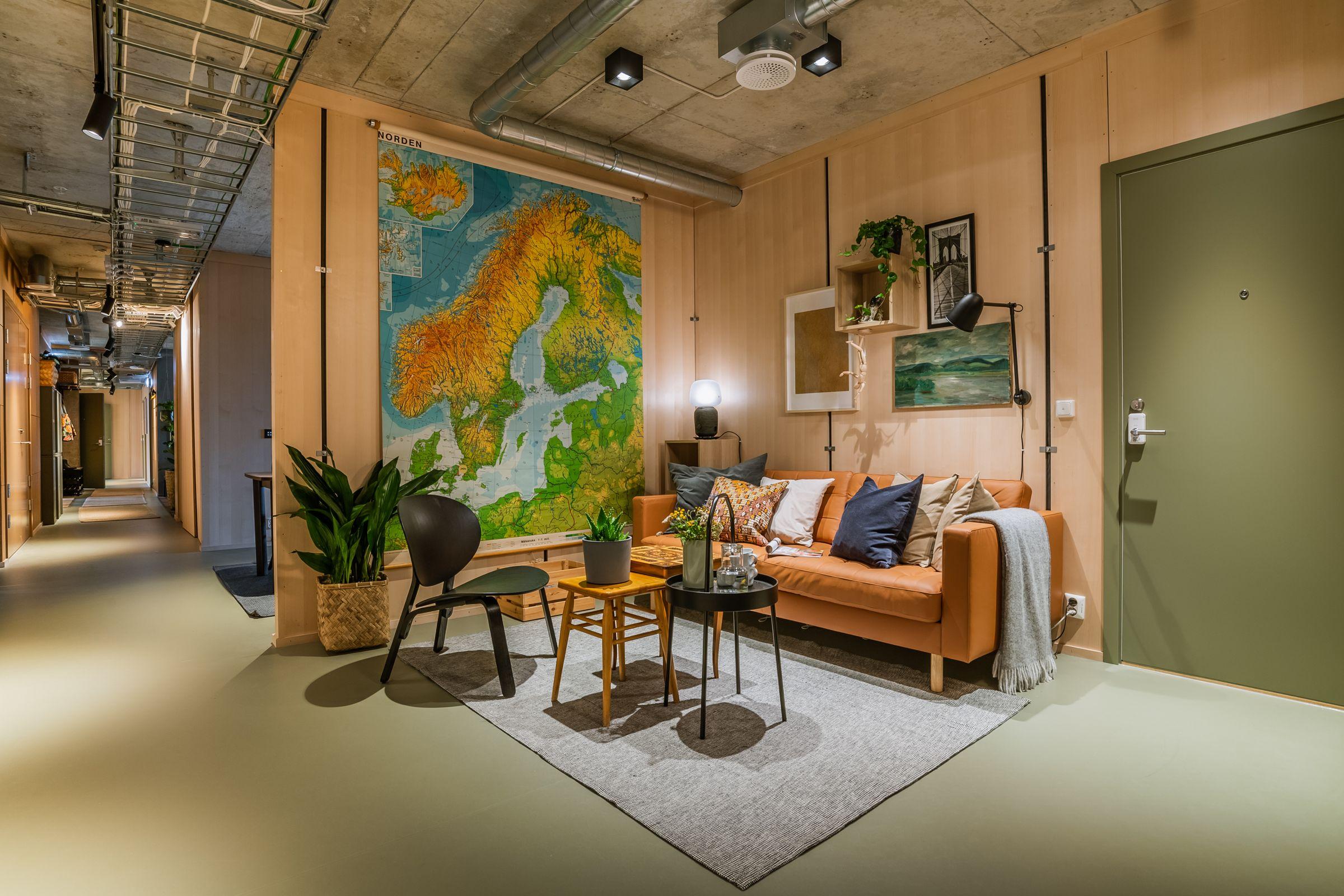 Bilde av en sofasone med sitteplasser og et stort kart på veggen i OBOS Living Lab.